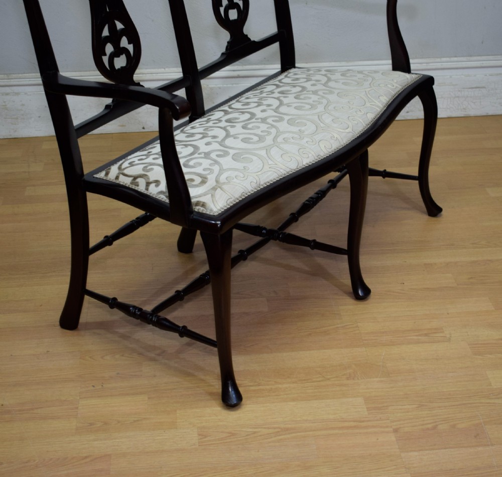 A late Victorian dark mahogany double chair-back settee featuring pierced splats, curved arms, cabriole front legs, and a patterned fabric seat. View XII