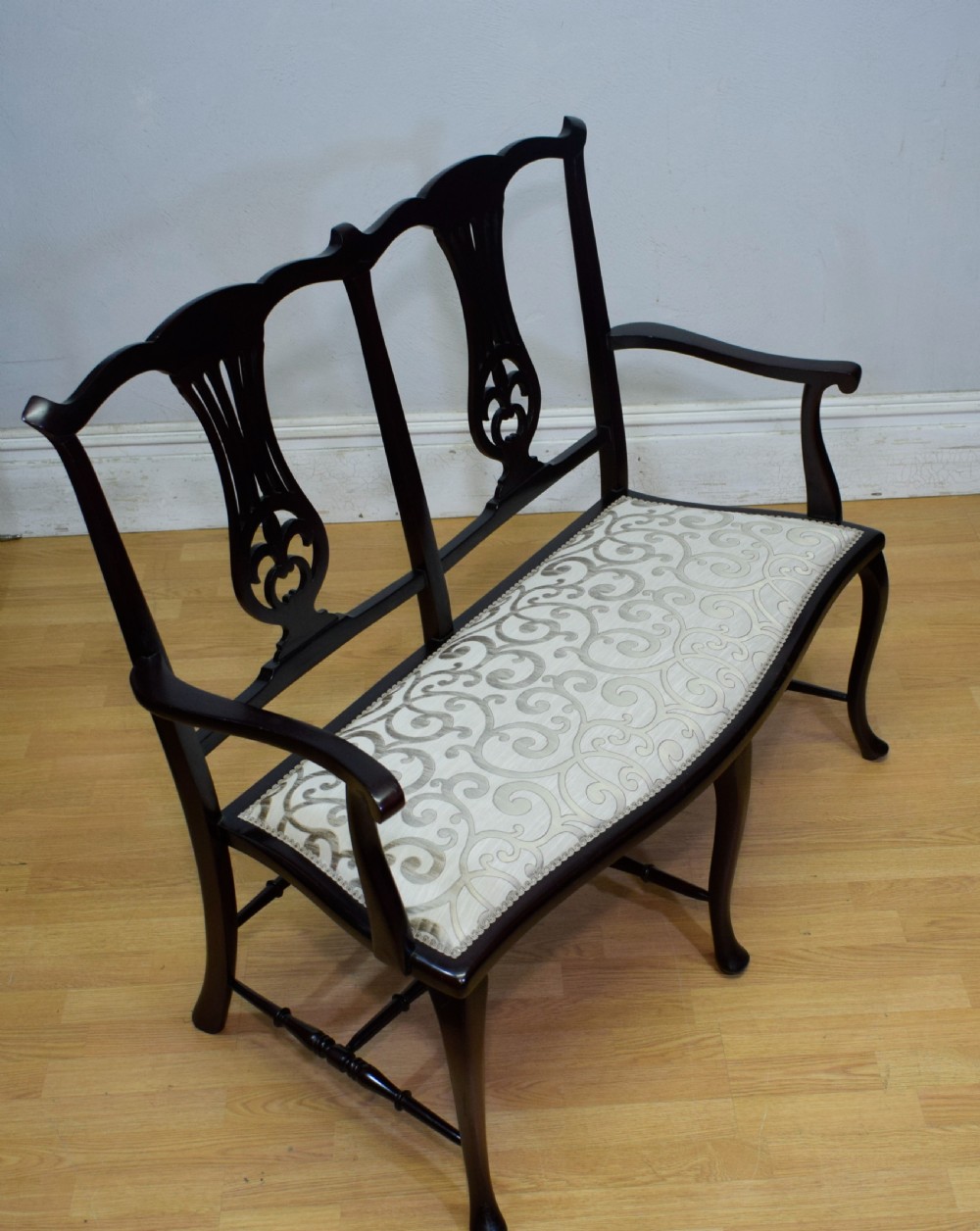 A late Victorian dark mahogany double chair-back settee featuring pierced splats, curved arms, cabriole front legs, and a patterned fabric seat. View XIII