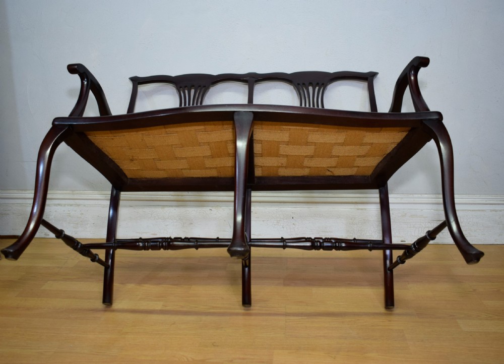 A late Victorian dark mahogany double chair-back settee featuring pierced splats, curved arms, cabriole front legs, and a patterned fabric seat. View XV
