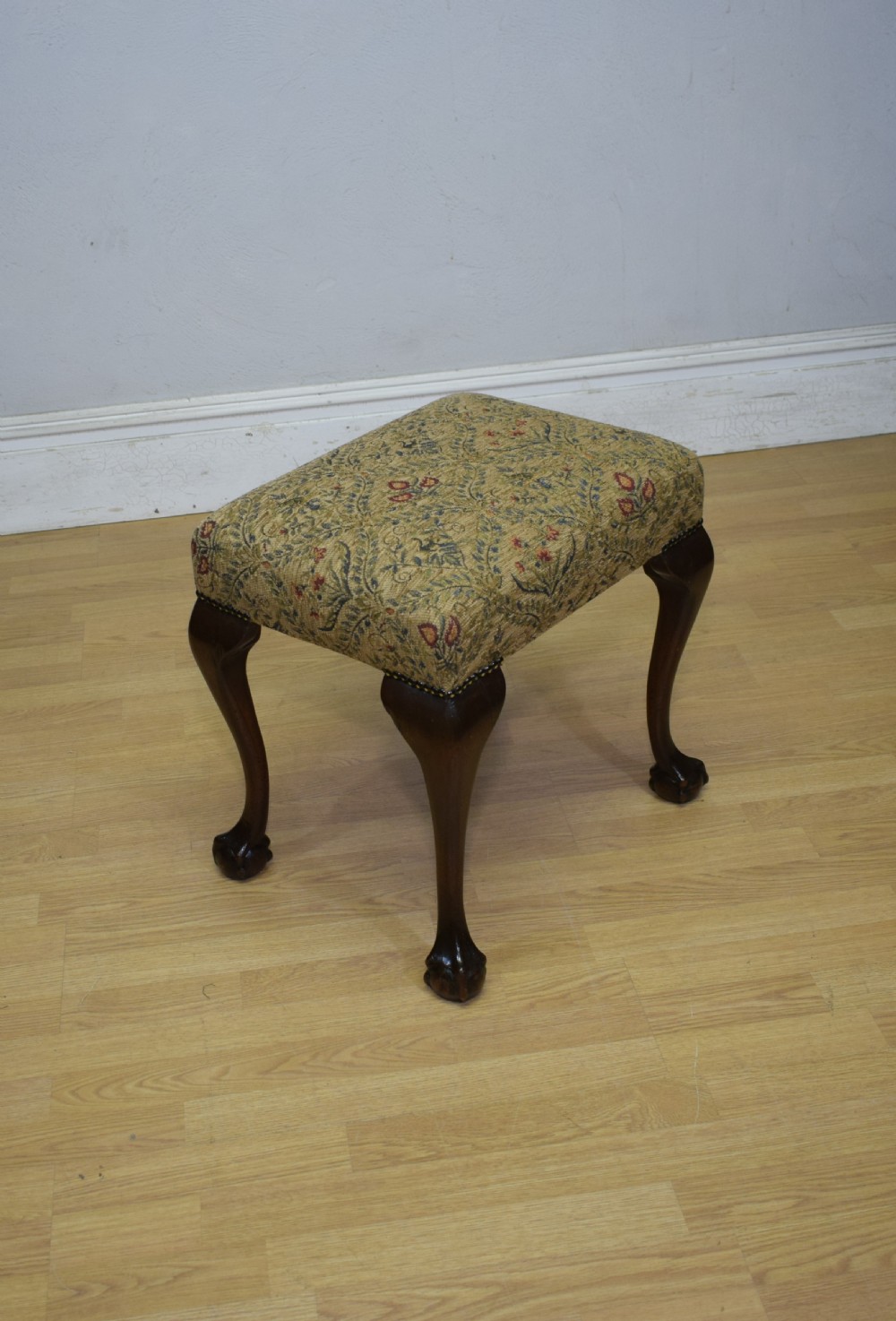 A square Chippendale style stool upholstered in floral patterned fabric with dark mahogany cabriole legs and claw-and-ball feet. View V