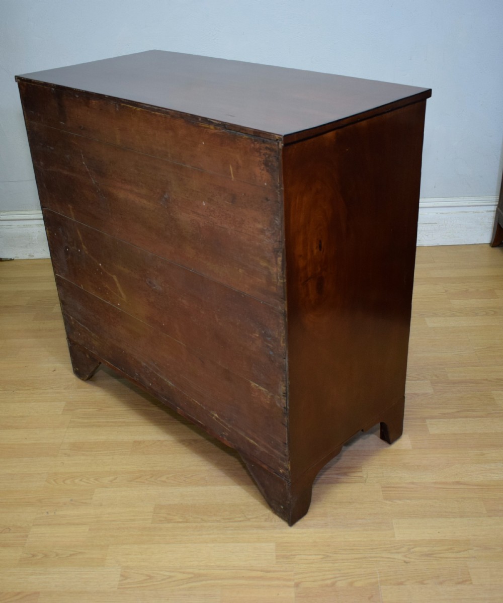 A Regency period mahogany chest of drawers featuring a two short over three long graduated drawer layout with polished brass oval handles and bracket feet. View XII