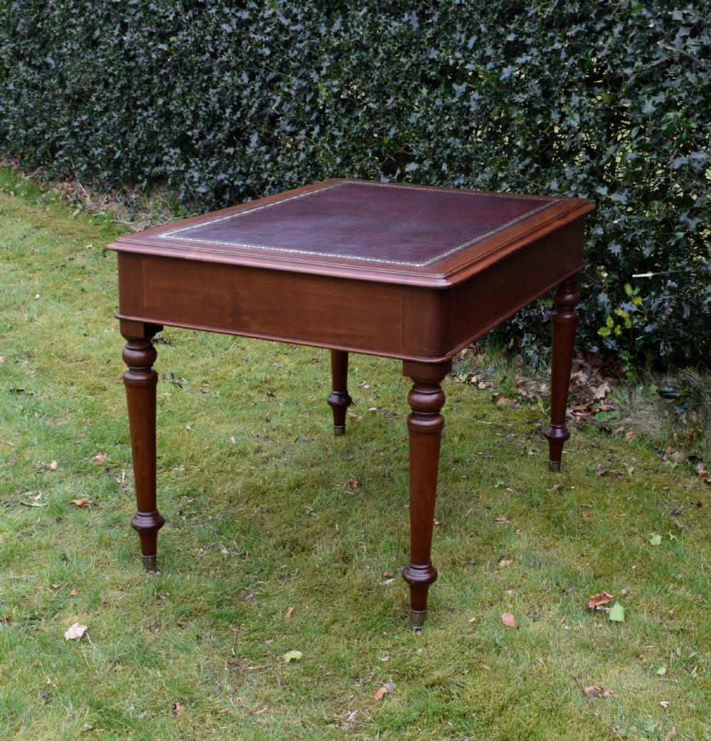 A Victorian mahogany writing table featuring a dark red leather insert top, two frieze drawers with wooden knobs, and four turned legs. View XIV