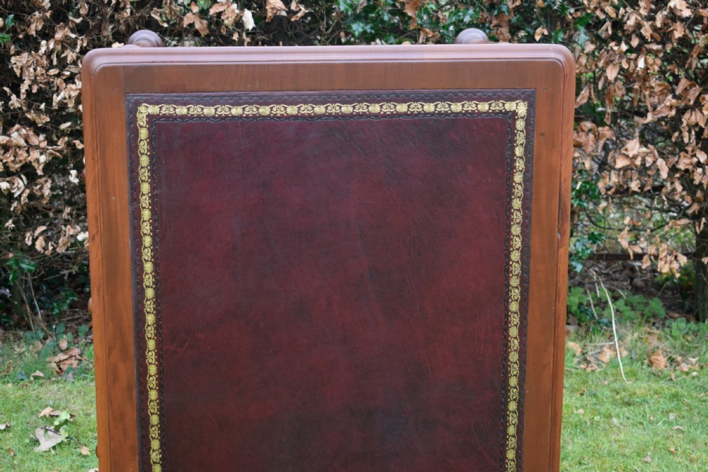 A Victorian mahogany writing table featuring a dark red leather insert top, two frieze drawers with wooden knobs, and four turned legs. View XVIII