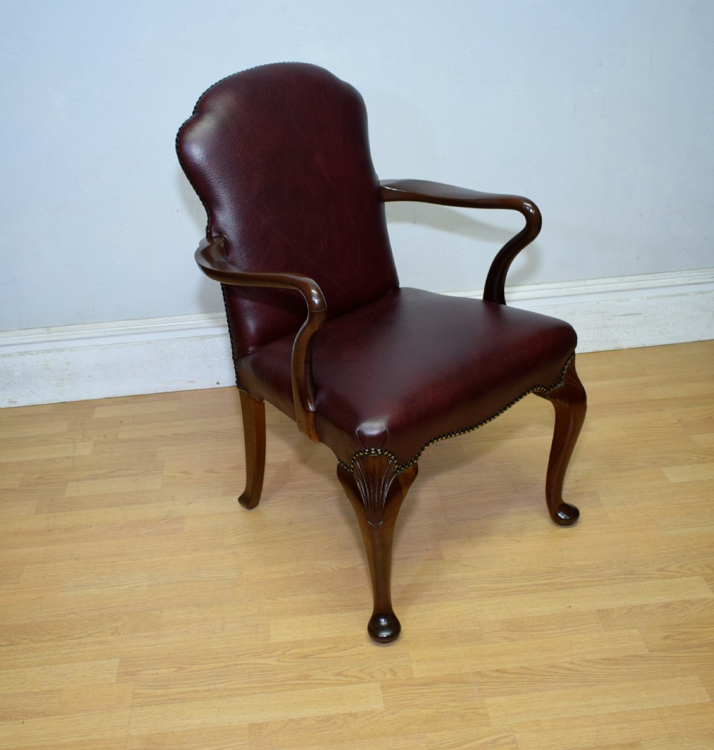 A dark burgundy leather upholstered library armchair featuring a carved walnut frame, open curved armrests, brass studding, and front cabriole legs. View II