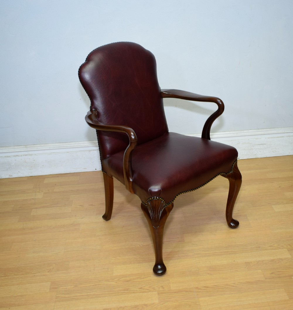 A dark burgundy leather upholstered library armchair featuring a carved walnut frame, open curved armrests, brass studding, and front cabriole legs. View III