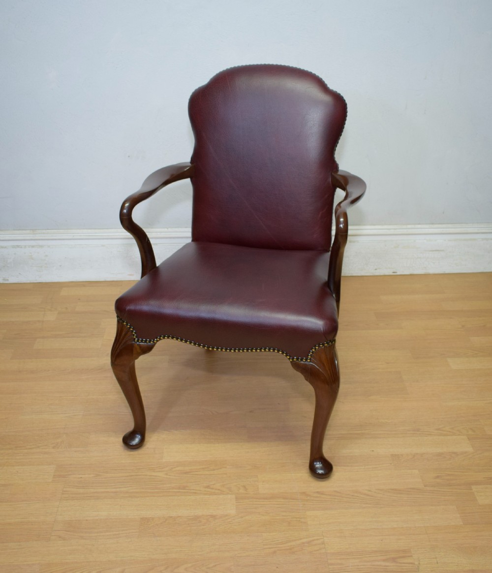 A dark burgundy leather upholstered library armchair featuring a carved walnut frame, open curved armrests, brass studding, and front cabriole legs. View VIII