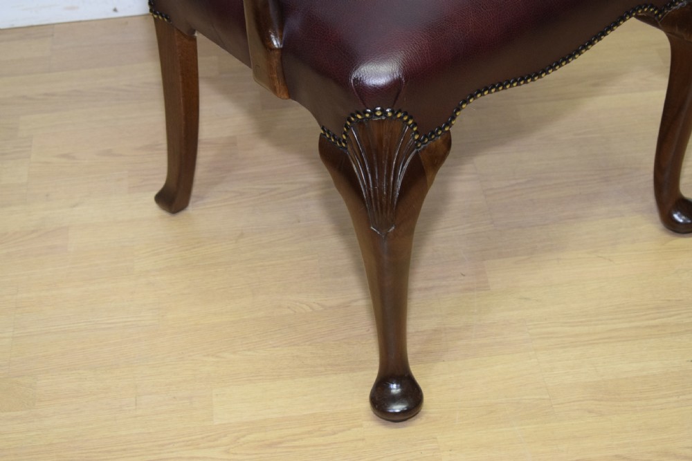A dark burgundy leather upholstered library armchair featuring a carved walnut frame, open curved armrests, brass studding, and front cabriole legs. View XIV