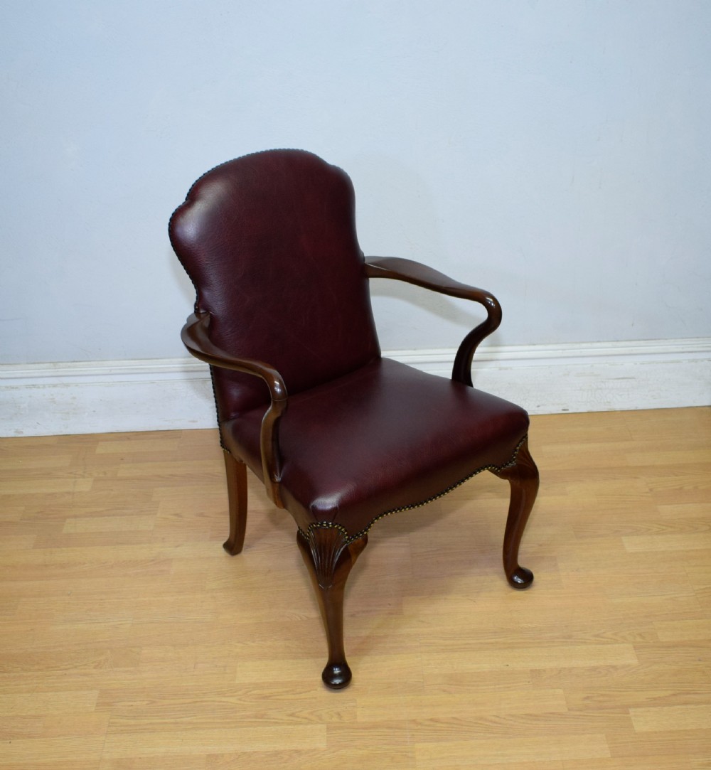 A dark burgundy leather upholstered library armchair featuring a carved walnut frame, open curved armrests, brass studding, and front cabriole legs. View XV