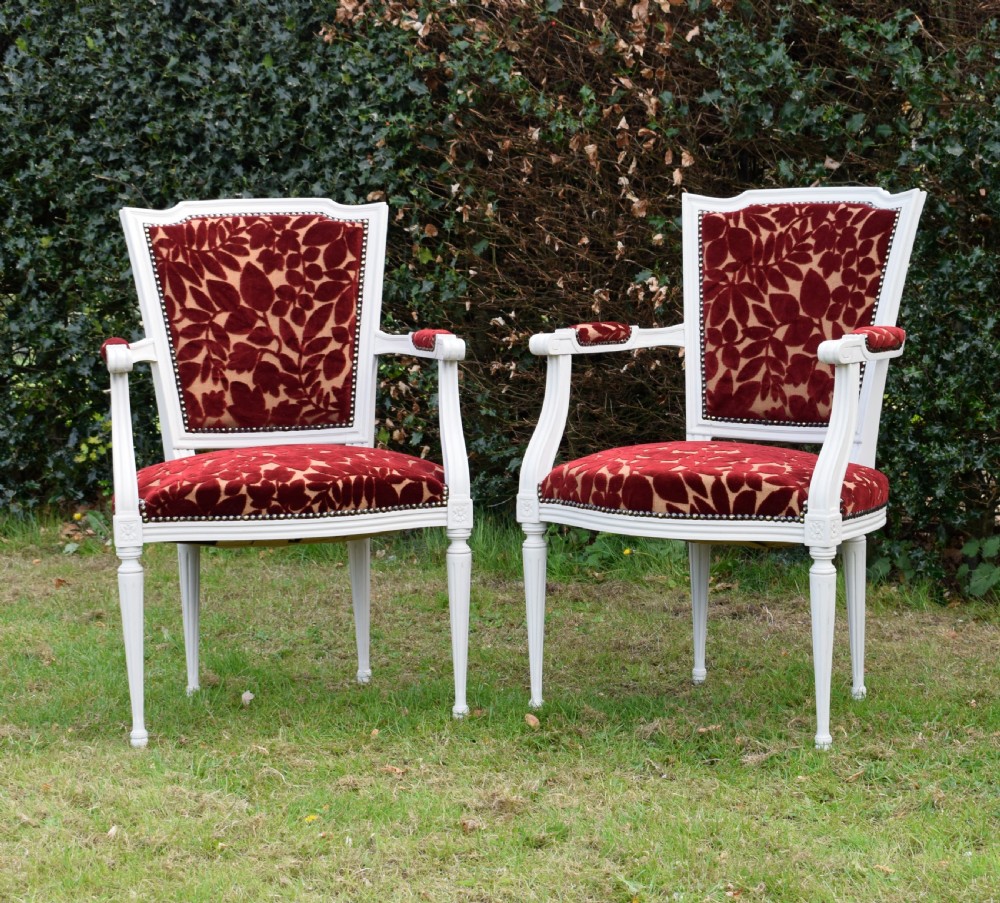 A pair of white painted open armchairs featuring fluted legs, padded armrests, and burgundy botanical cut velvet upholstery secured with brass studs. View III