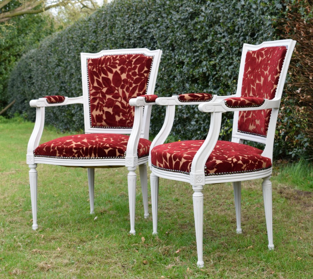 A pair of white painted open armchairs featuring fluted legs, padded armrests, and burgundy botanical cut velvet upholstery secured with brass studs. View IV