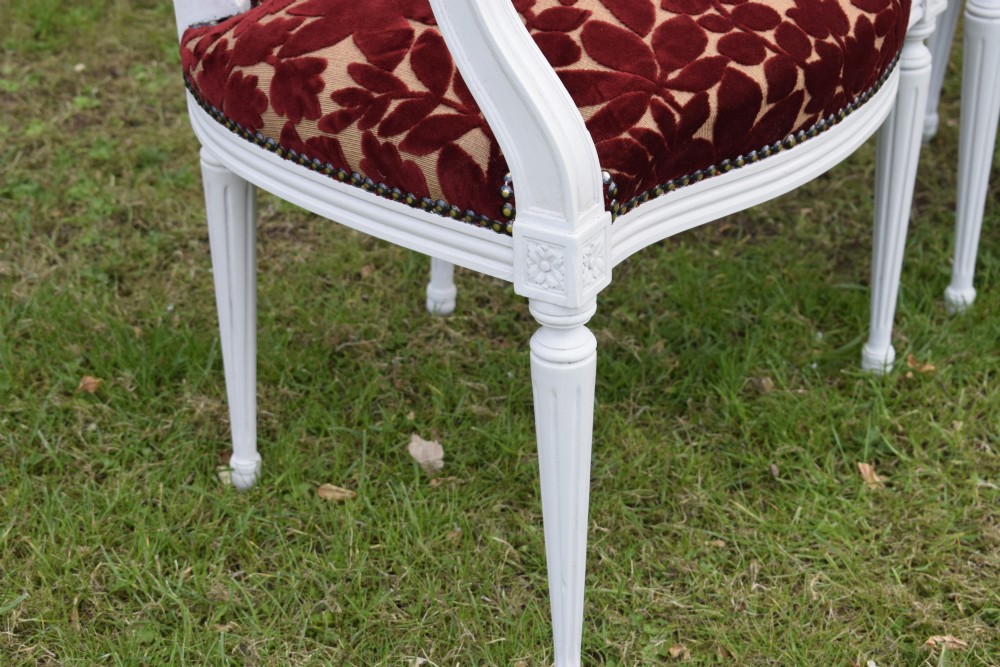 A pair of white painted open armchairs featuring fluted legs, padded armrests, and burgundy botanical cut velvet upholstery secured with brass studs. View VIII