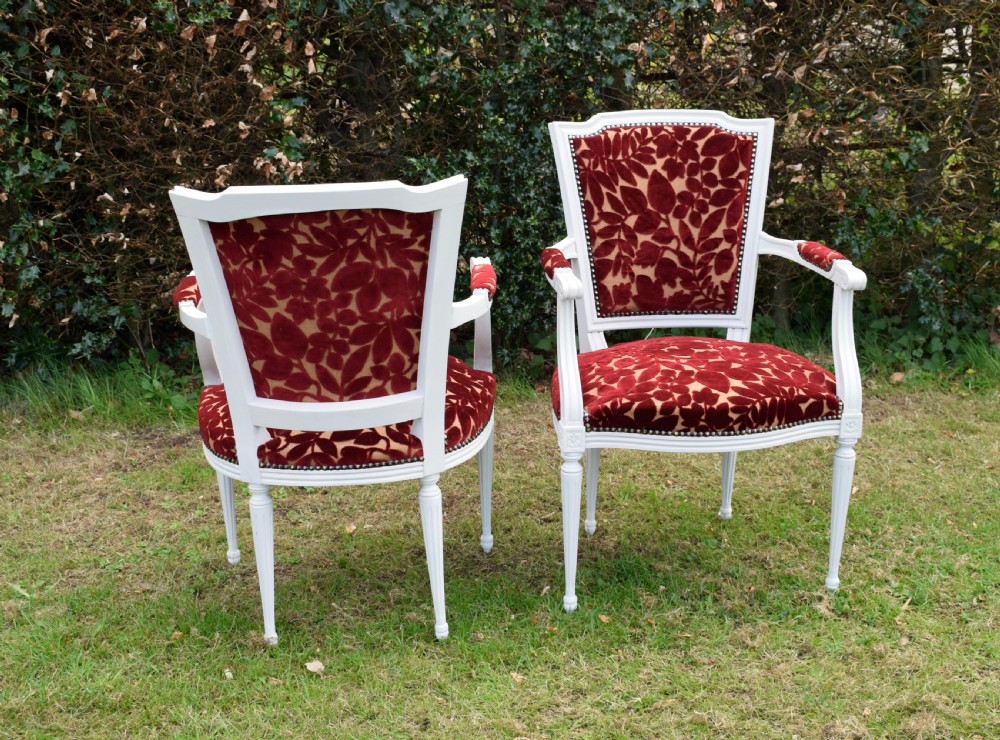 A pair of white painted open armchairs featuring fluted legs, padded armrests, and burgundy botanical cut velvet upholstery secured with brass studs. View XVII