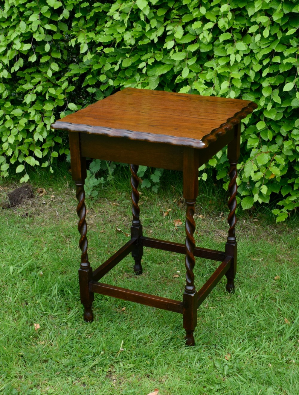 A dark brown square oak side table featuring a scalloped piecrust edge, four barley twist turned legs, and a lower square stretcher frame.