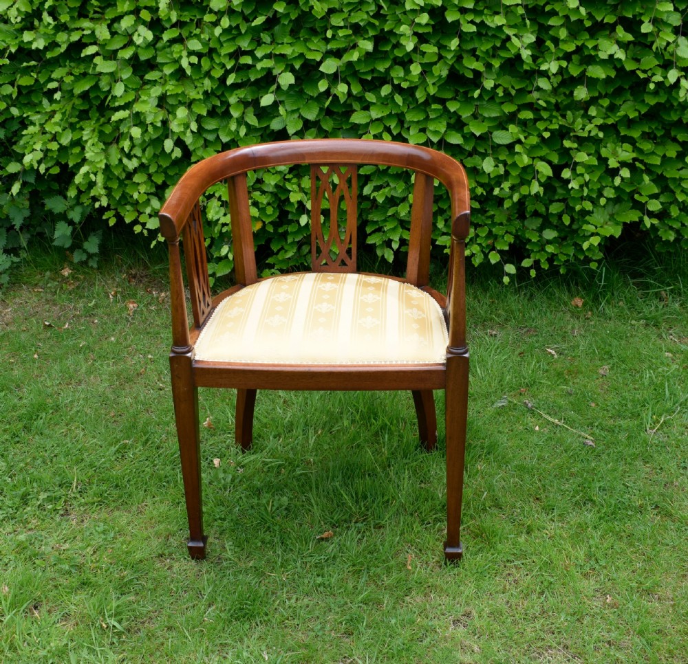 An Edwardian inlaid mahogany tub chair featuring a rounded crest rail, pierced geometric splats, and a gold striped upholstered seat. View III