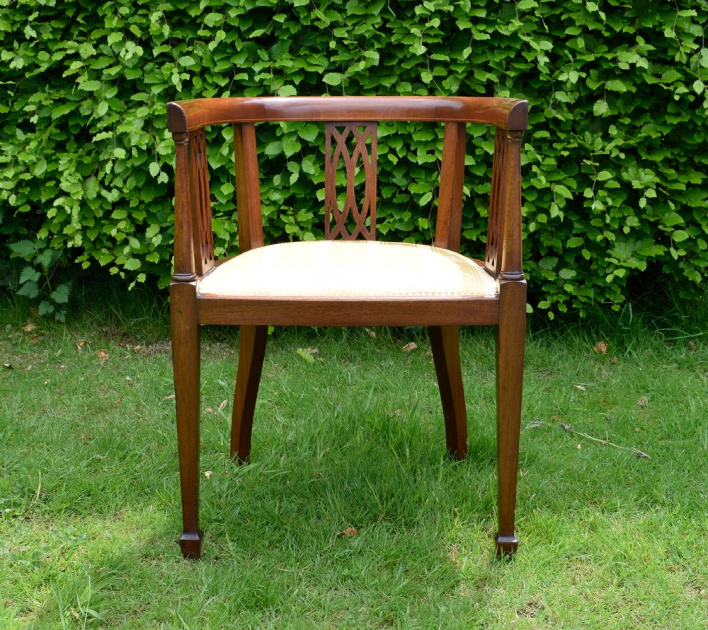 An Edwardian inlaid mahogany tub chair featuring a rounded crest rail, pierced geometric splats, and a gold striped upholstered seat. View V