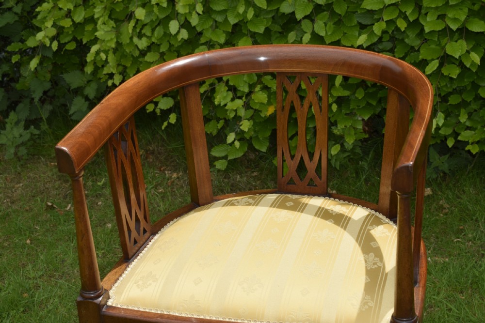 An Edwardian inlaid mahogany tub chair featuring a rounded crest rail, pierced geometric splats, and a gold striped upholstered seat. View VI