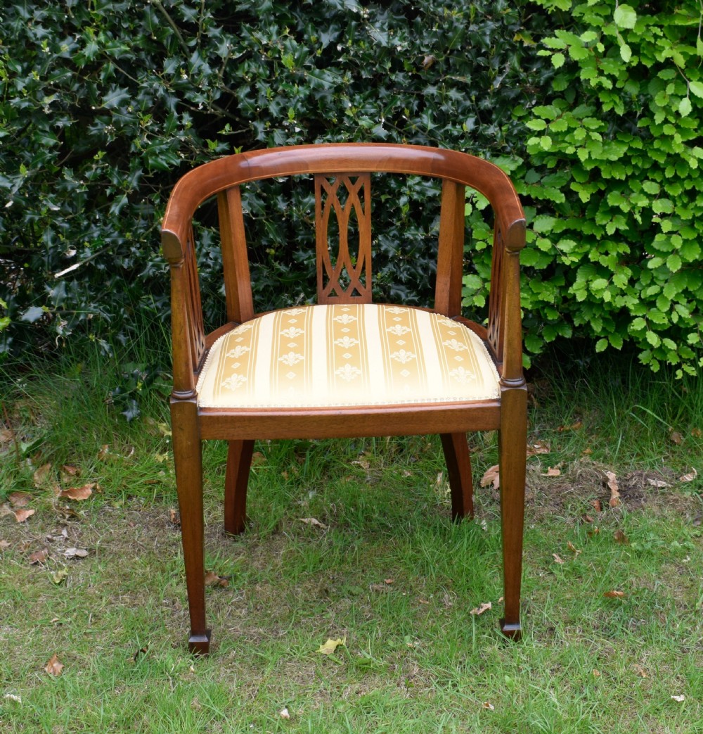 An Edwardian inlaid mahogany tub chair featuring a rounded crest rail, pierced geometric splats, and a gold striped upholstered seat. View VII