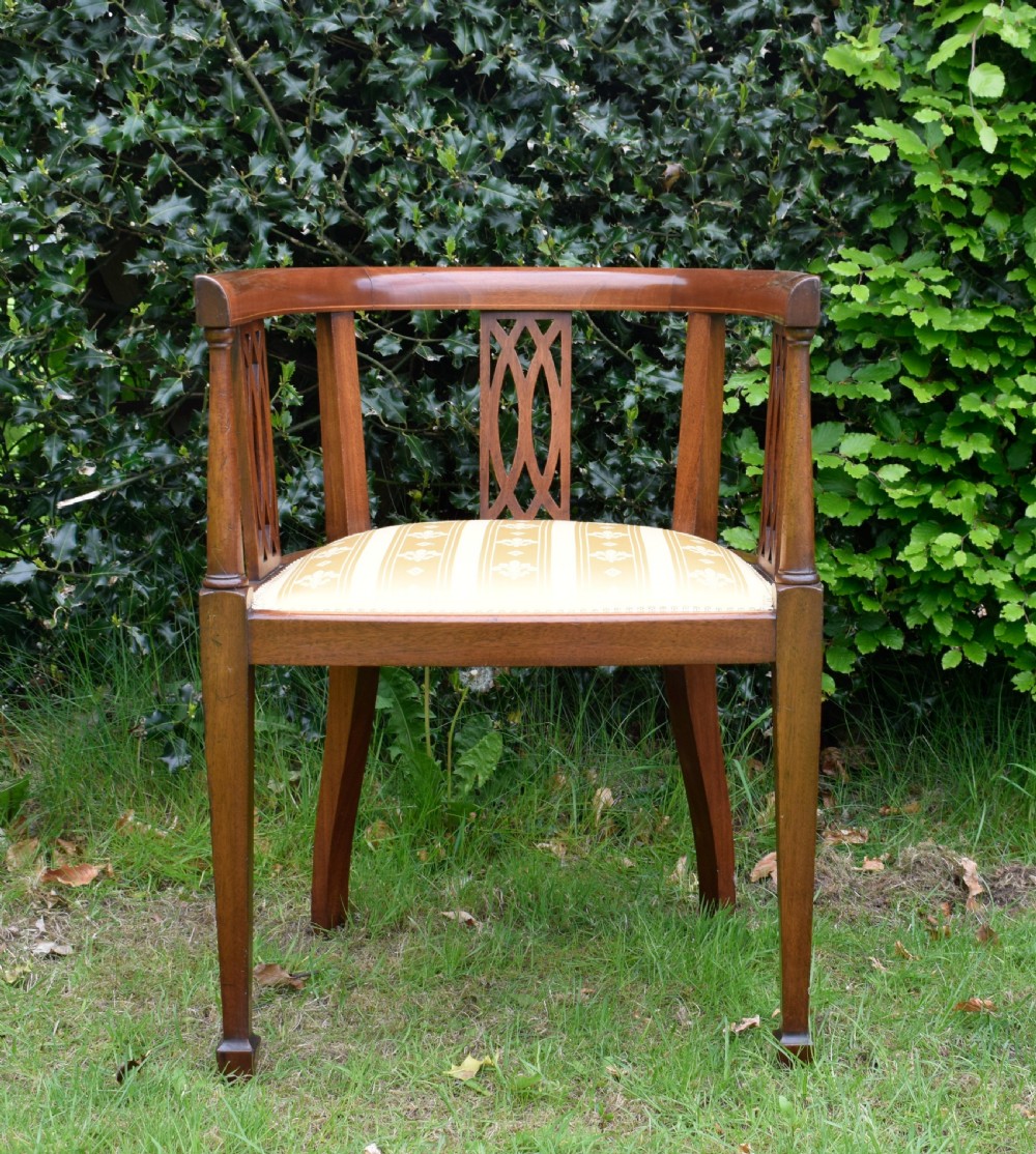 An Edwardian inlaid mahogany tub chair featuring a rounded crest rail, pierced geometric splats, and a gold striped upholstered seat. View VIII