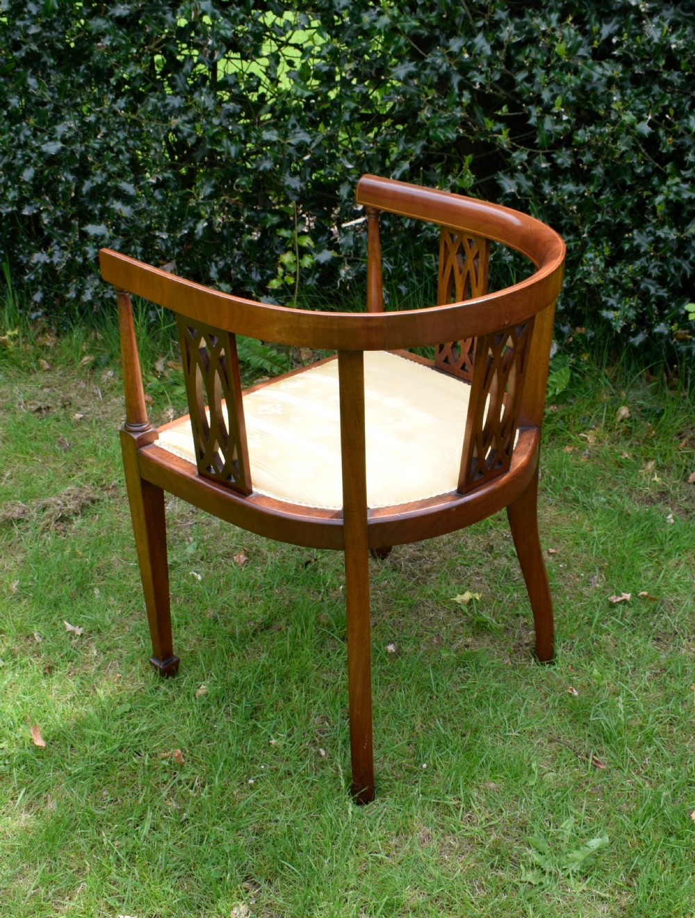 An Edwardian inlaid mahogany tub chair featuring a rounded crest rail, pierced geometric splats, and a gold striped upholstered seat. View XII