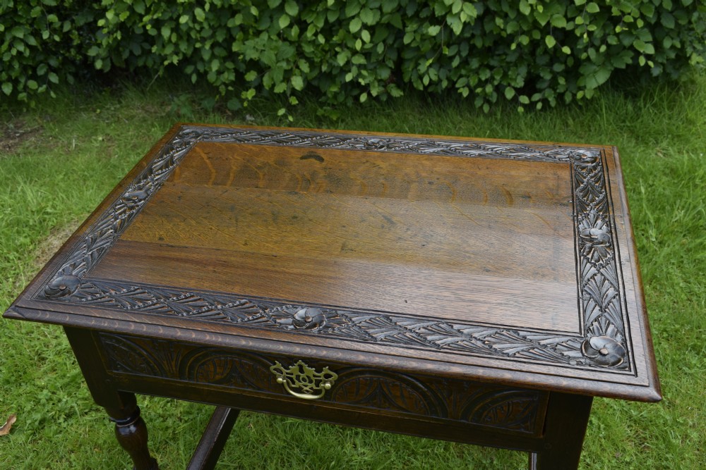A dark oak 17th-century lowboy table featuring a carved rectangular top, a single carved drawer front with a central brass handle, turned legs, and low wooden stretchers. View III