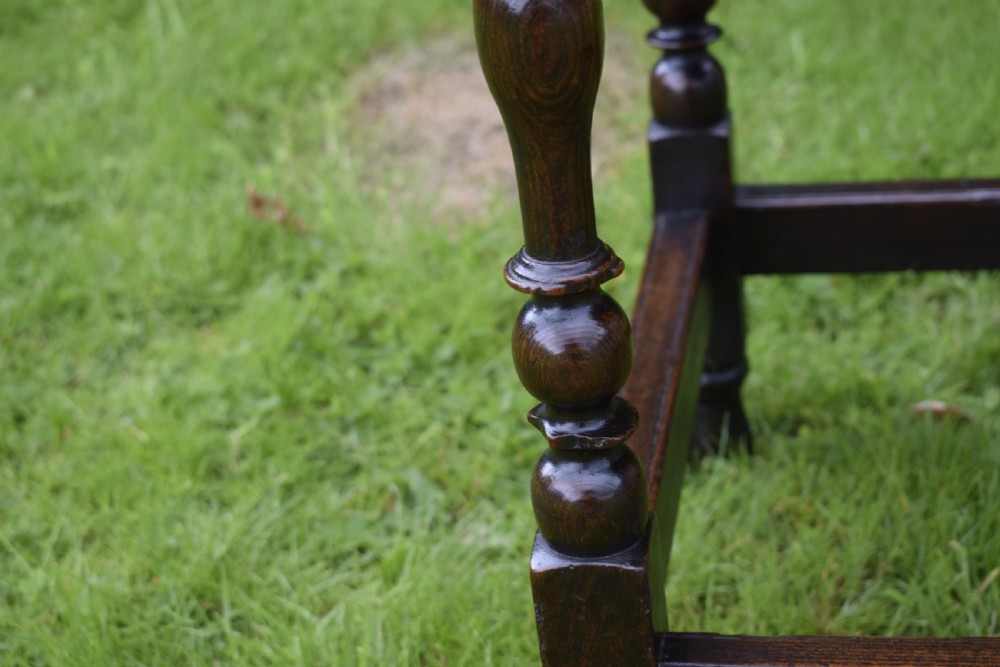A dark oak 17th-century lowboy table featuring a carved rectangular top, a single carved drawer front with a central brass handle, turned legs, and low wooden stretchers. View XV