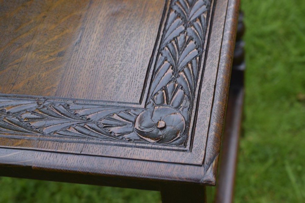 A dark oak 17th-century lowboy table featuring a carved rectangular top, a single carved drawer front with a central brass handle, turned legs, and low wooden stretchers. View XXI