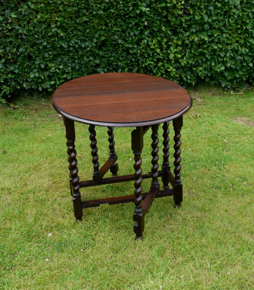 A dark oak round gateleg dining table featuring spirally turned barley twist legs and low stretchers. View II