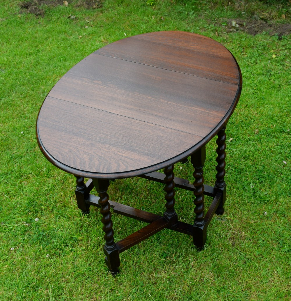 A dark oak round gateleg dining table featuring spirally turned barley twist legs and low stretchers. View III