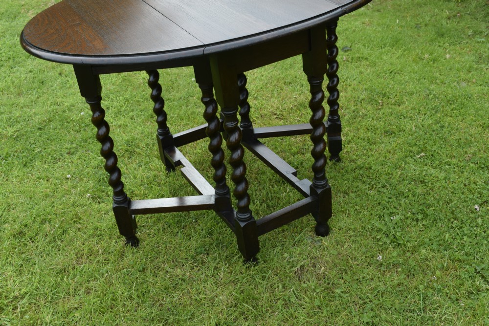 A dark oak round gateleg dining table featuring spirally turned barley twist legs and low stretchers. View V