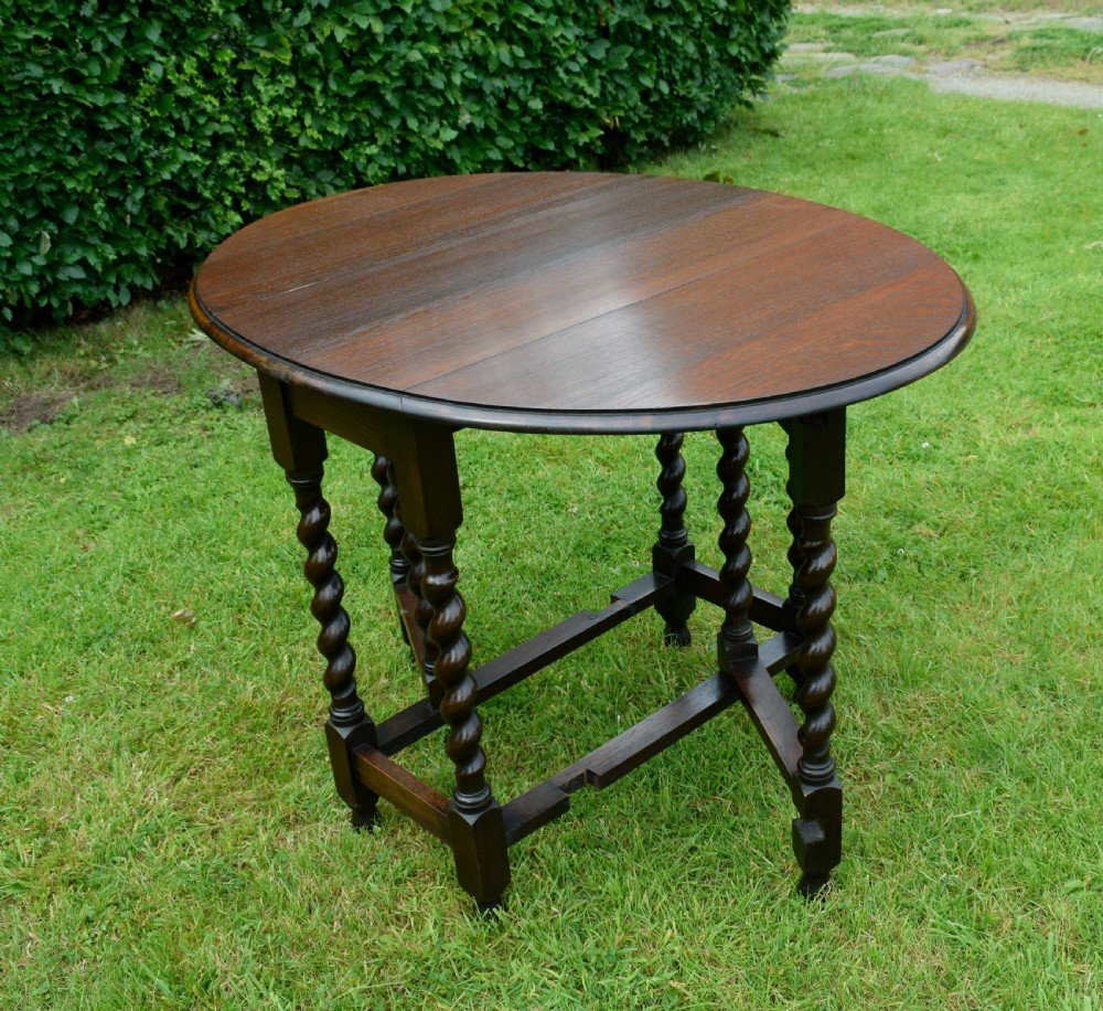 A dark oak round gateleg dining table featuring spirally turned barley twist legs and low stretchers. View VI