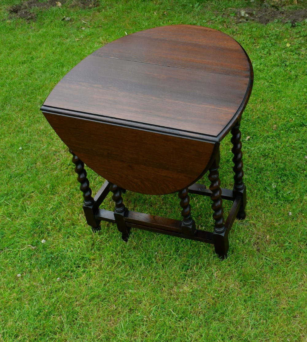 A dark oak round gateleg dining table featuring spirally turned barley twist legs and low stretchers. View VII