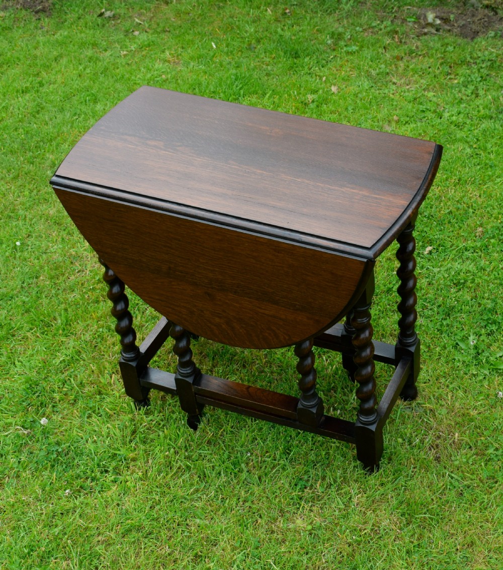 A dark oak round gateleg dining table featuring spirally turned barley twist legs and low stretchers. View VIII