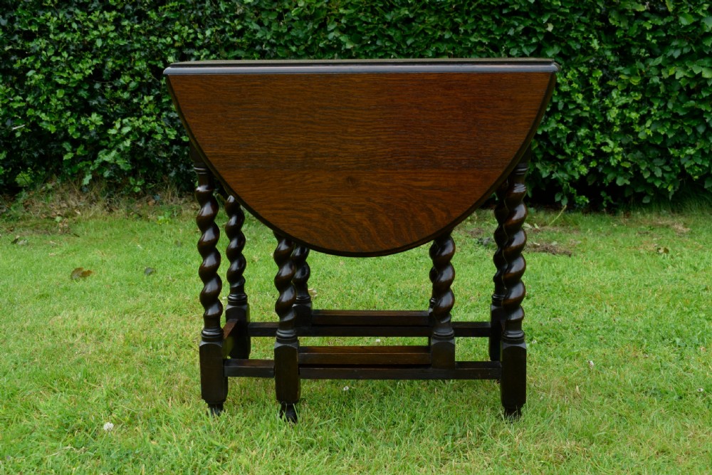 A dark oak round gateleg dining table featuring spirally turned barley twist legs and low stretchers. View X