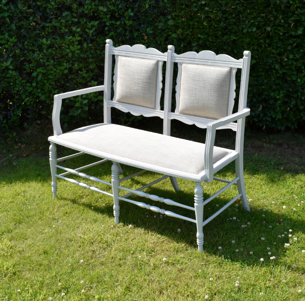 A white painted Edwardian two-seater bench featuring turned legs and neutral linen upholstered seat and back panels. View III