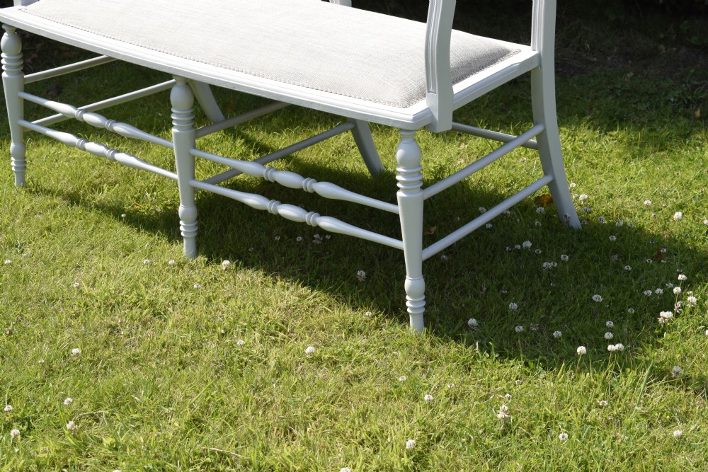 A white painted Edwardian two-seater bench featuring turned legs and neutral linen upholstered seat and back panels. View IV
