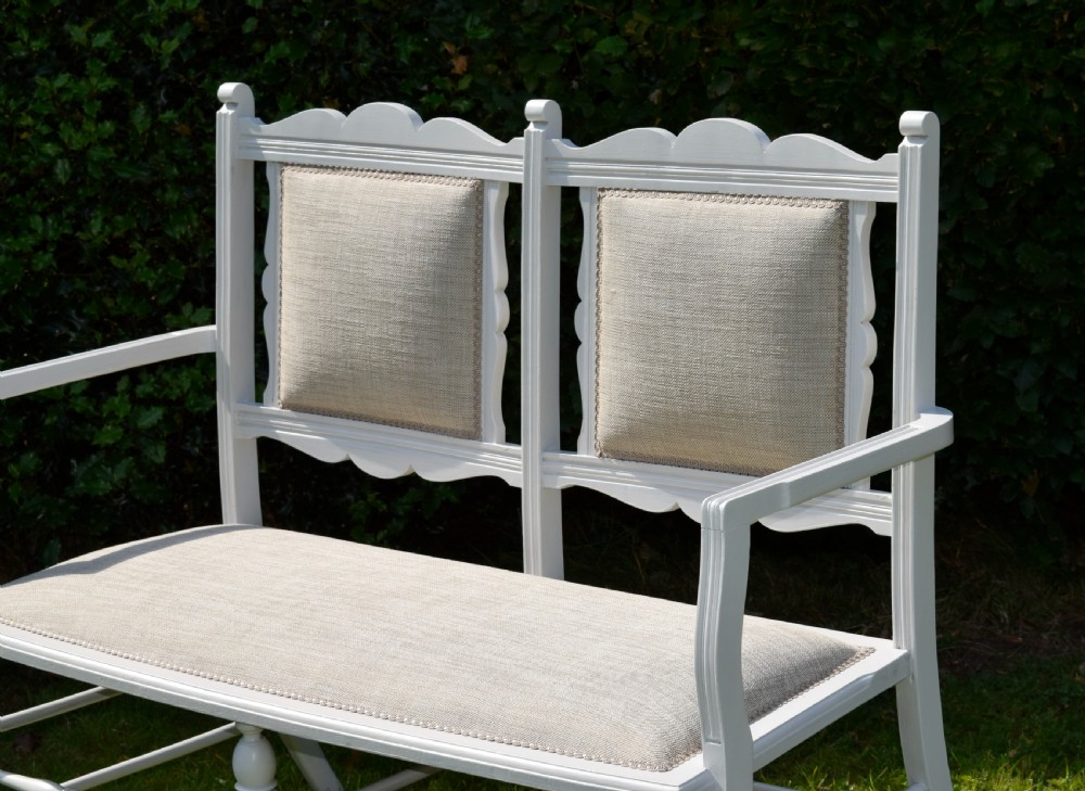 A white painted Edwardian two-seater bench featuring turned legs and neutral linen upholstered seat and back panels. View V