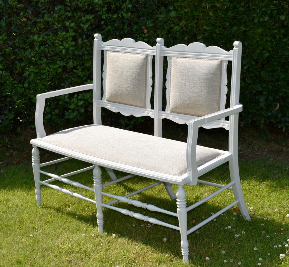 A white painted Edwardian two-seater bench featuring turned legs and neutral linen upholstered seat and back panels. View VII
