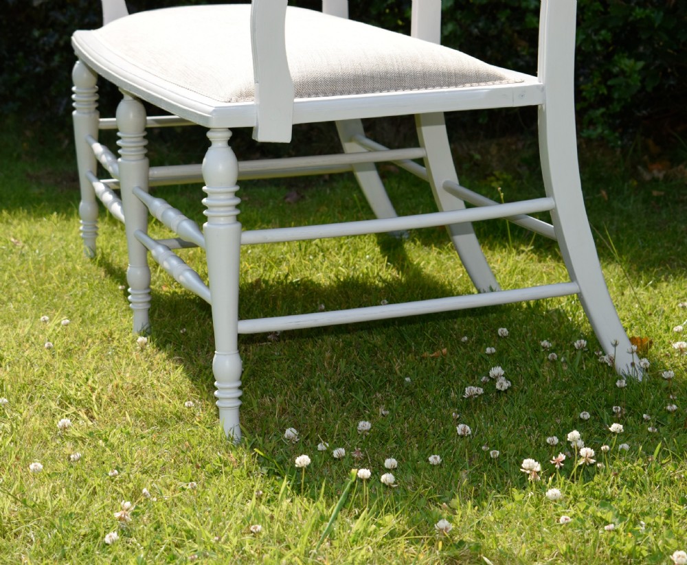 A white painted Edwardian two-seater bench featuring turned legs and neutral linen upholstered seat and back panels. View XII
