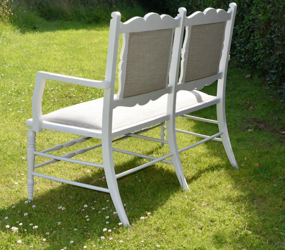 A white painted Edwardian two-seater bench featuring turned legs and neutral linen upholstered seat and back panels. View XIII