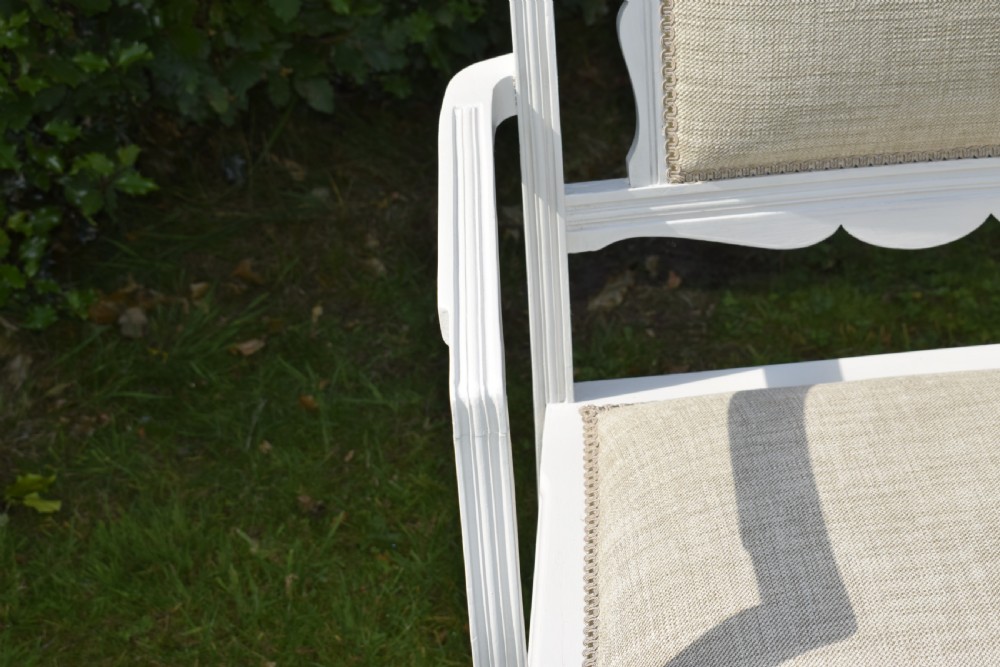A white painted Edwardian two-seater bench featuring turned legs and neutral linen upholstered seat and back panels. View XV
