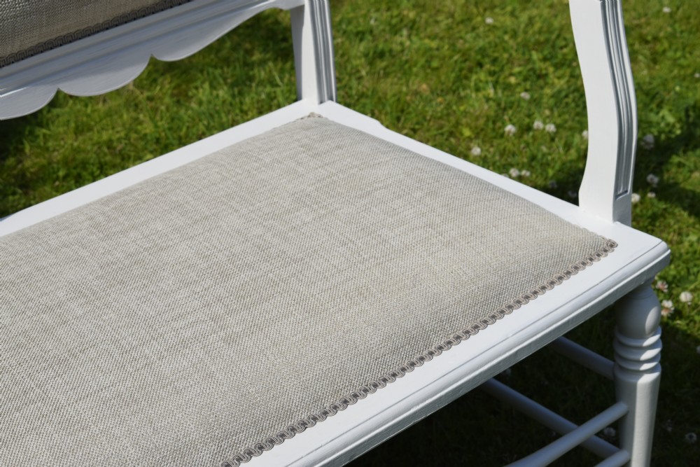 A white painted Edwardian two-seater bench featuring turned legs and neutral linen upholstered seat and back panels. View XVII