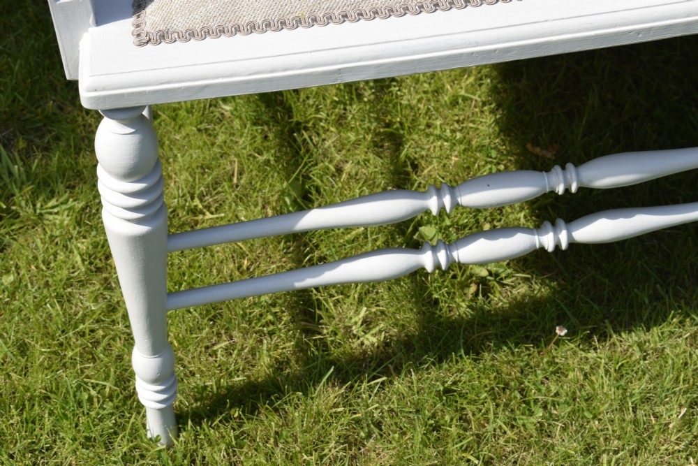 A white painted Edwardian two-seater bench featuring turned legs and neutral linen upholstered seat and back panels. View XVIII