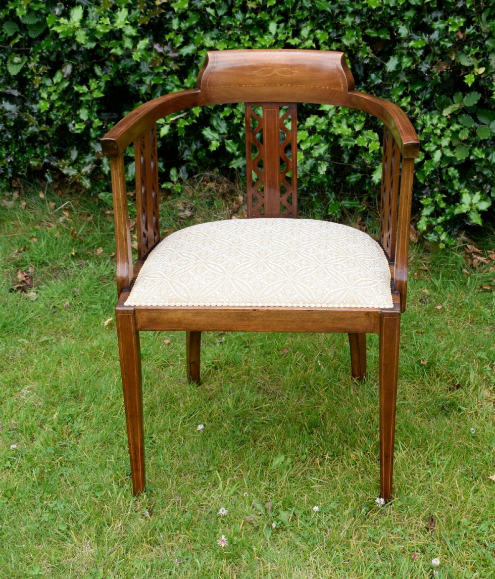 An Edwardian mahogany tub armchair featuring satinwood inlay, pierced lattice back splats, curved arms, and a light pattern-upholstered seat. View II