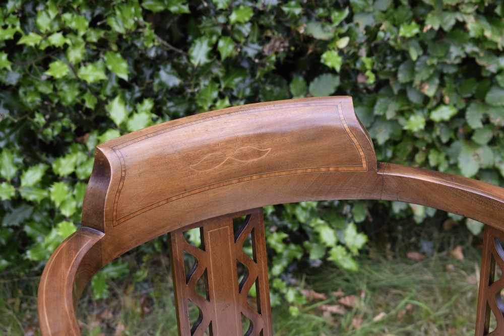 An Edwardian mahogany tub armchair featuring satinwood inlay, pierced lattice back splats, curved arms, and a light pattern-upholstered seat. View III