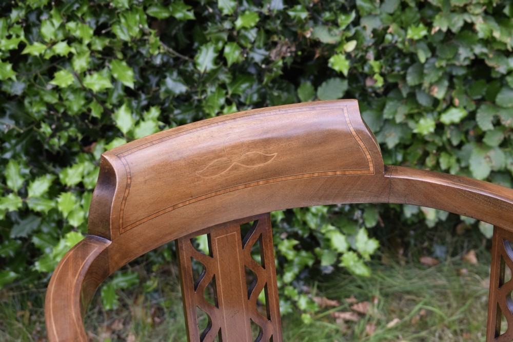 An Edwardian mahogany tub armchair featuring satinwood inlay, pierced lattice back splats, curved arms, and a light pattern-upholstered seat. View IV