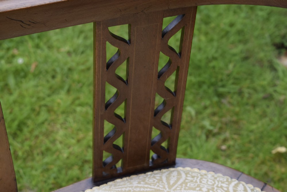 An Edwardian mahogany tub armchair featuring satinwood inlay, pierced lattice back splats, curved arms, and a light pattern-upholstered seat. View VII
