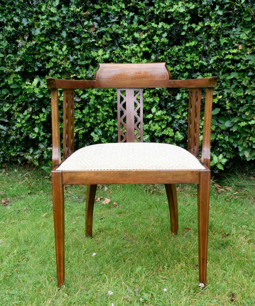 An Edwardian mahogany tub armchair featuring satinwood inlay, pierced lattice back splats, curved arms, and a light pattern-upholstered seat. View VIII