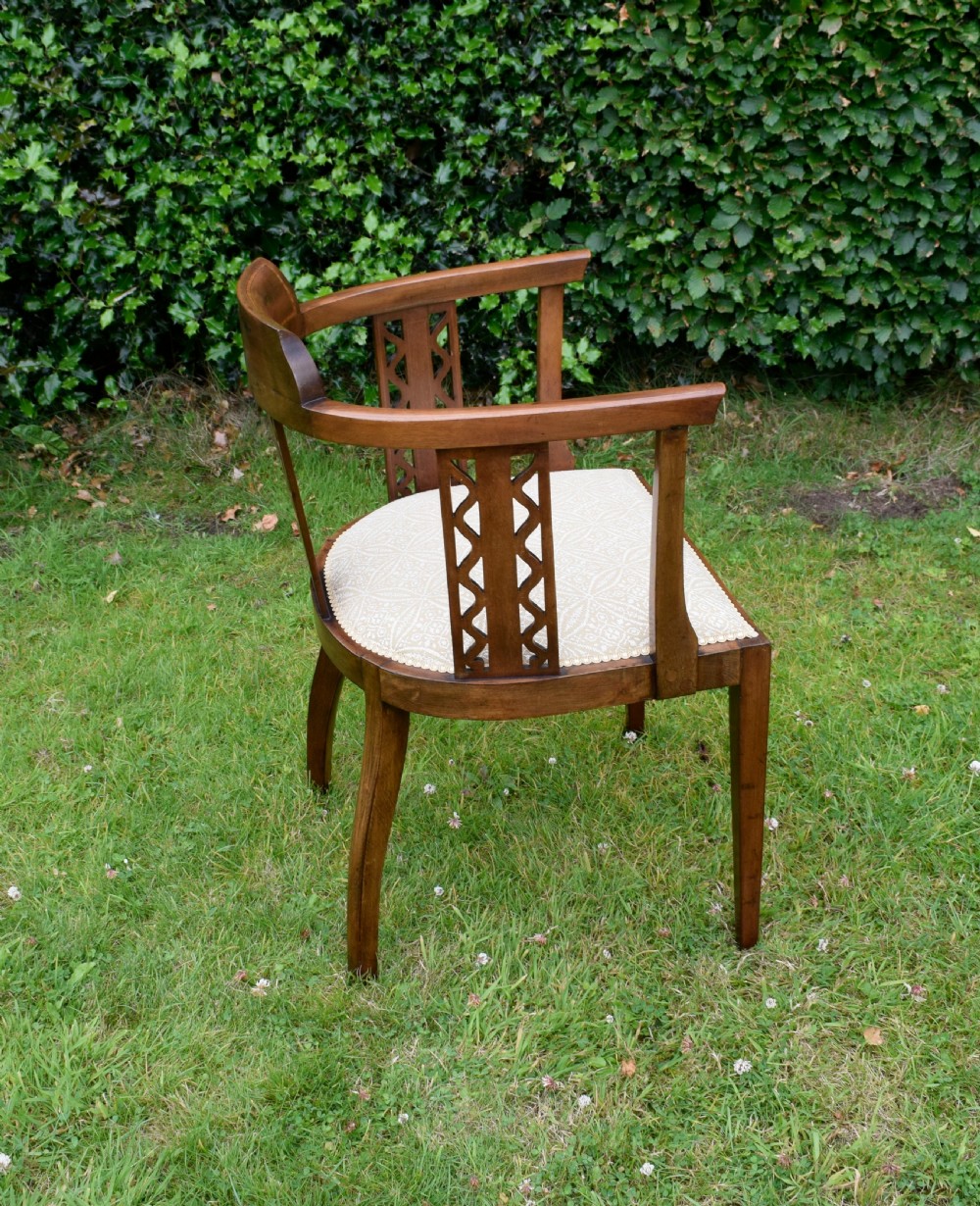 An Edwardian mahogany tub armchair featuring satinwood inlay, pierced lattice back splats, curved arms, and a light pattern-upholstered seat. View X