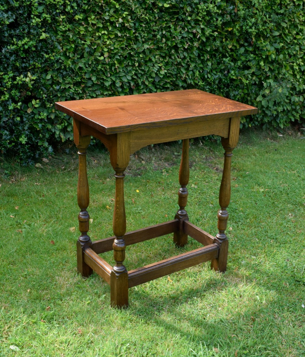 A tall rectangular dark oak side table featuring turned legs, a shaped apron, and lower perimeter box stretchers. View II