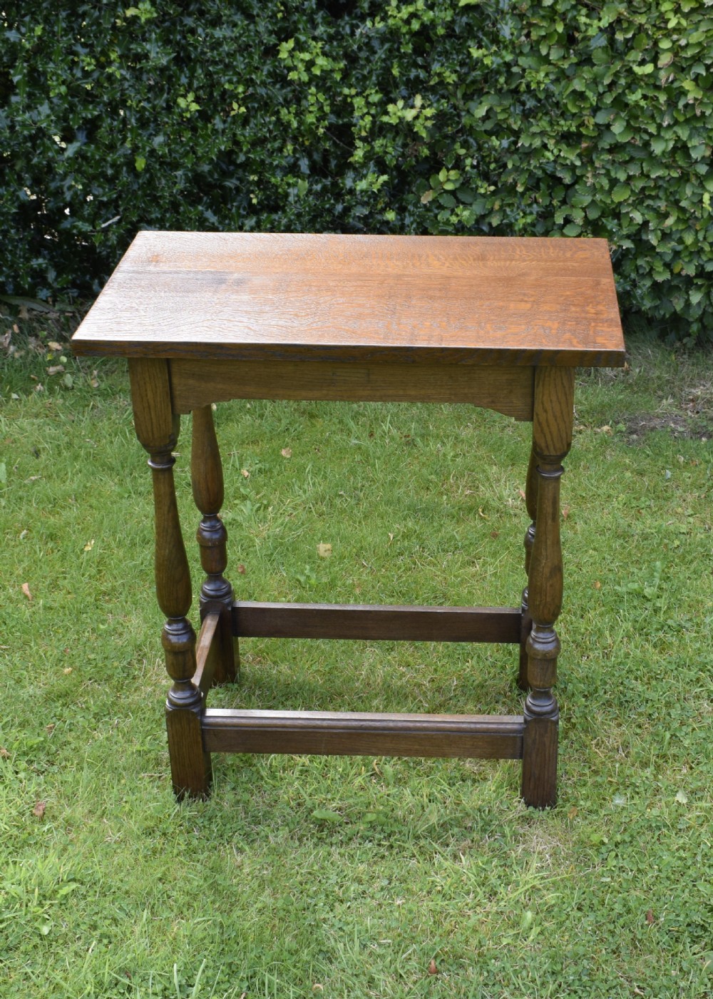 A tall rectangular dark oak side table featuring turned legs, a shaped apron, and lower perimeter box stretchers. View III